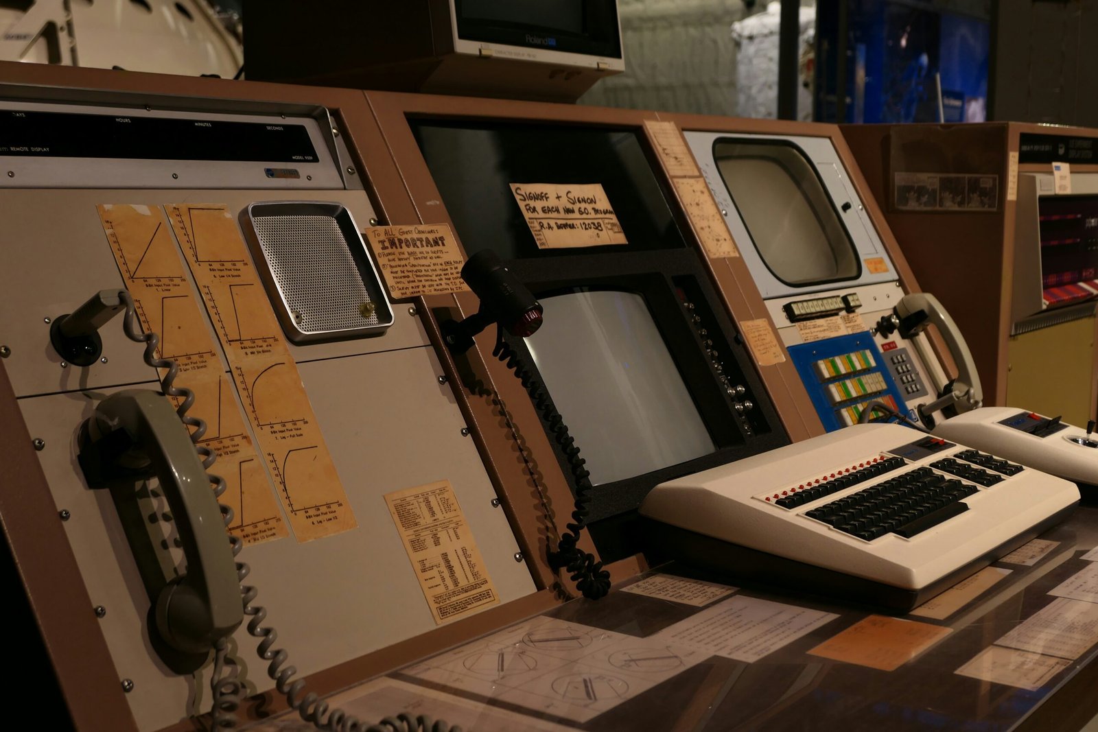 Retro mission control station with screens, telephones, and a classic computer keyboard.